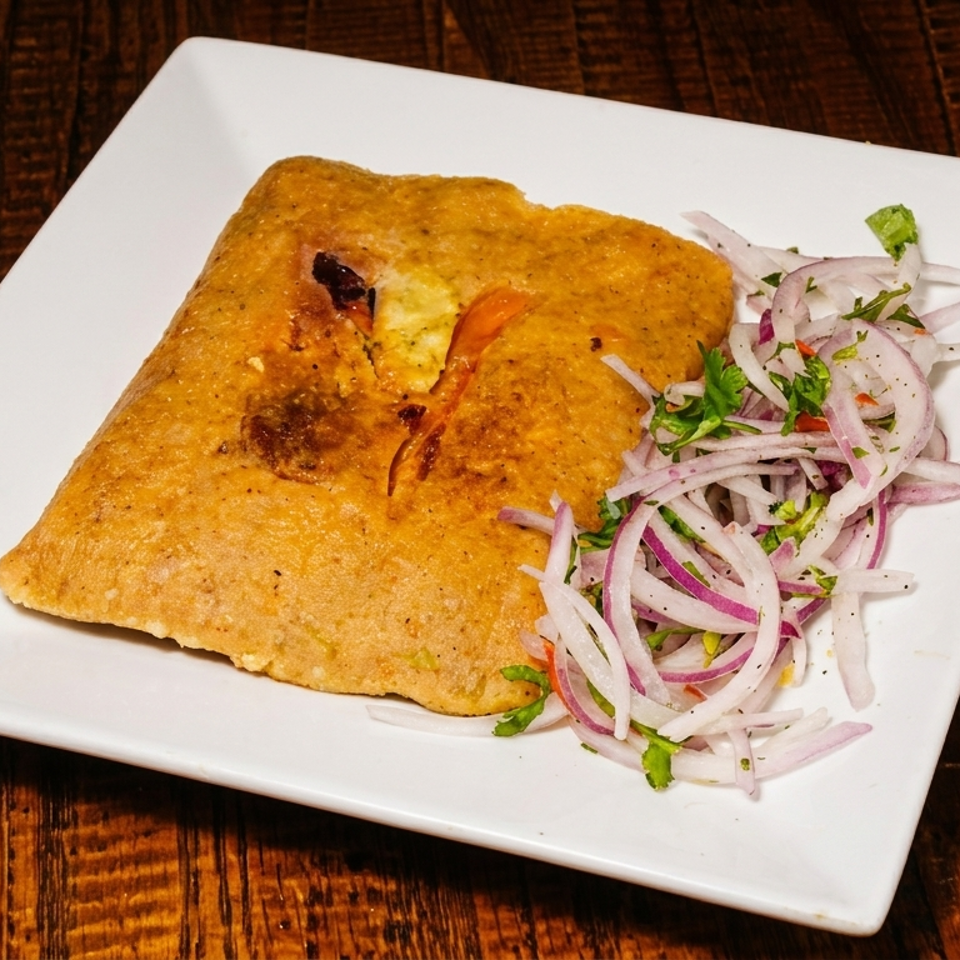 A Peruvian tamale with a side of red onion and cilantro salsa on a white plate.